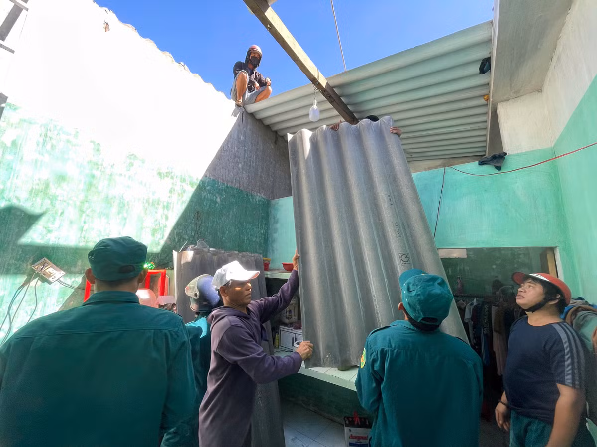 Dân quân xã An Phú điều động toàn bộ lực lượng sử dụng tấm lợp xi măng khắc phục phần mái nhà dân bị thổi bay hoàn toàn trong đêm.