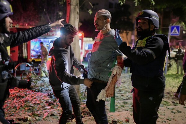 Các nhân viên cứu hộ băng bó và sơ cứu vết thương khắp cơ thể cho một người đàn ông sau khi tên lửa Iran đánh trúng một khu vực đông người ở Tel Aviv.