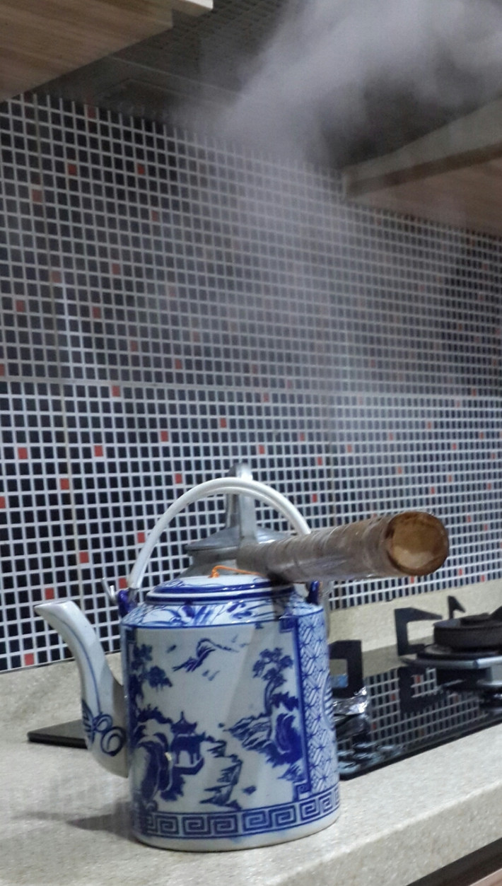 Lắp ống xông vào vòi ấm, dùng một vật làm giá đỡ cho ống xông không bị rơi và đảm bảo luồng hơi được thoát ra tốt nhất. (Trong hình dùng ấm hãm trè xanh để kê). Khi quan sát thấy hơi thoát ra khỏi ống là các mẹ có thể cho các bé xông được.