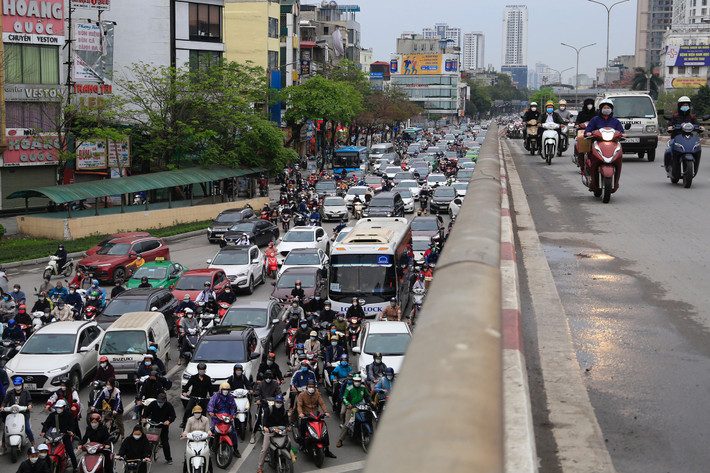 Phía dưới cầu vượt, hàng dài xe cộ xếp hàng chờ đèn tín hiệu.