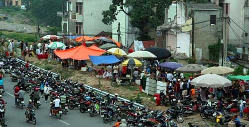 Đây là dự án đường Văn Cao - Hồ Tây được thực hiện nhằm chào mừng Đại lễ 1.000 năm Thăng Long - Hà Nội. Dự án này đã được đầu tư hàng trăm tỷ đồng nhưng đến nay vẫn chưa hoàn thành. Những ngôi nhà bị đập nham nhở và bãi đất hoang ngổn ngang bê tông nhanh chóng trở thành khu chợ tạm mua bán chim.