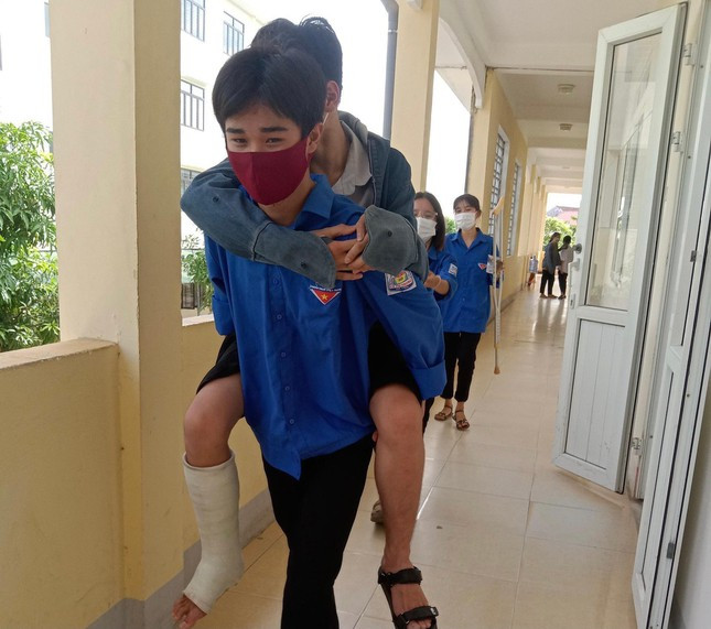 Chân còn bị đau do tai nạn, thí sinh Trần Văn Thắng được tình nguyện viên cõng vào phòng thi tại điểm trường Lý Tự Trọng (huyện Thạch Hà).