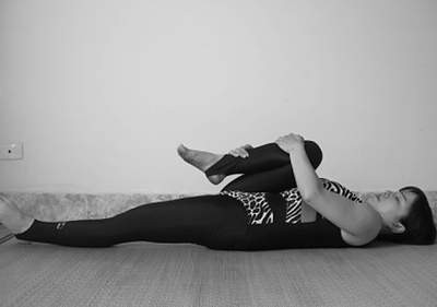 Cách tập yoga nóng. Động tác thoát hơi: Bạn nằm ngửa, hít thở trong khi co chân trái về sát ngực sao cho đùi trên sát bụng, chân phải duỗi thẳng trên sàn. Hai tay ôm chân trái gập. Nâng đầu dậy để gối chậm mũi. Dừng lại, nín thở. Thở ra, trở lại vị trí ban đầu. Lặp lại tương tự với chân phải.
