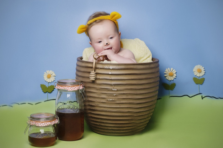 Em bé dễ thương này đóng vai chú gấu Pooh ngồi nhấm nháp mật ong.