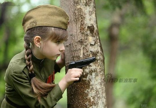 Bộ ảnh được thực hiện trong rừng với màu xanh làm nền chủ đạo nên càng làm nổi bật làn da trắng hồng của cô bé. Trong shot hình này, cô bé trông như một nữ chiến sĩ anh dũng của nước Nga.