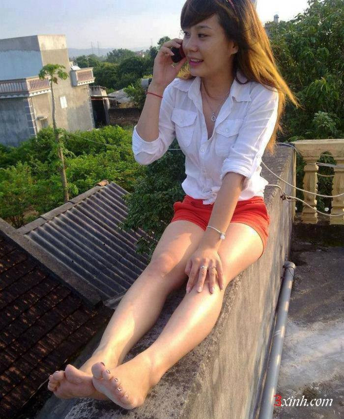 Đang nói chuyện điện thoại nhưng nữ sinh vẫn không quên pose ảnh khoe đôi chân của mình trên lan can của sân thượng.