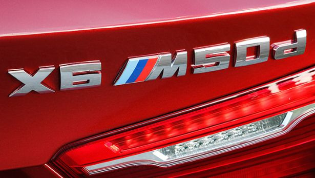Logo xe trắng bạc nổi bật trên nền sơn đỏ chói lóa.