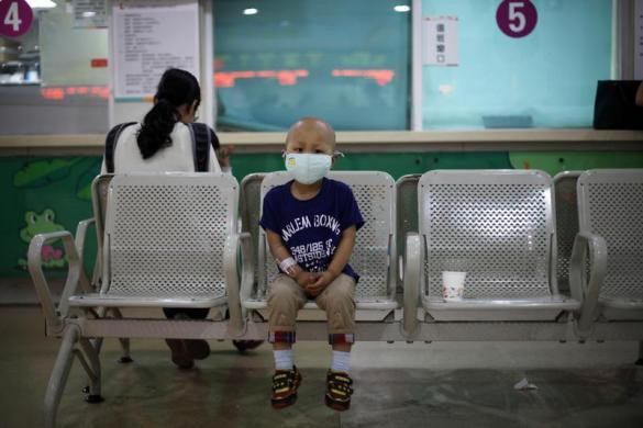 Niuniu ngồi trên ghế chờ mẹ đi trả tiền hóa đơn y tế cho phương pháp hóa trị liệu tại Bệnh viện trẻ em Thượng Hải.