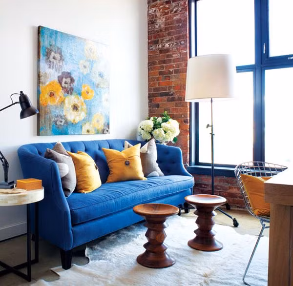 Một chiếc sofa xanh cô-ban sẽ làm cho phòng khách của bạn ấn tượng và thời thượng hơn. Ngoài ra, nó còn tăng độ sáng cho căn phòng, góp phần làm nổi bức tường được trang trí bằng gạch thô và đồ nội thất bằng gỗ.