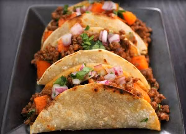 1. Tacos. Nó là loại bánh kẹp thịt với vỏ bánh được làm từ bột ngô còn nhân bánh được làm từ bất kỳ loại thịt nào như thịt lợn, thịt bò, thịt gà, cá nấu chín. Loại bánh này không thể thiếu được một chút sốt salsa và thường được ăn kèm với hành tây, rau mùi. Tacos có hai loại là vỏ bánh cứng và vỏ bánh mềm. Có rất nhiều loại bánh tacos nhưng loại tacos phổ biến nhất tại Mexico là Taco al Pastor. Nguyên liệu chính của Taco al Pastor là thịt lợn ướp gia vị, xiên que và nướng trên lửa.