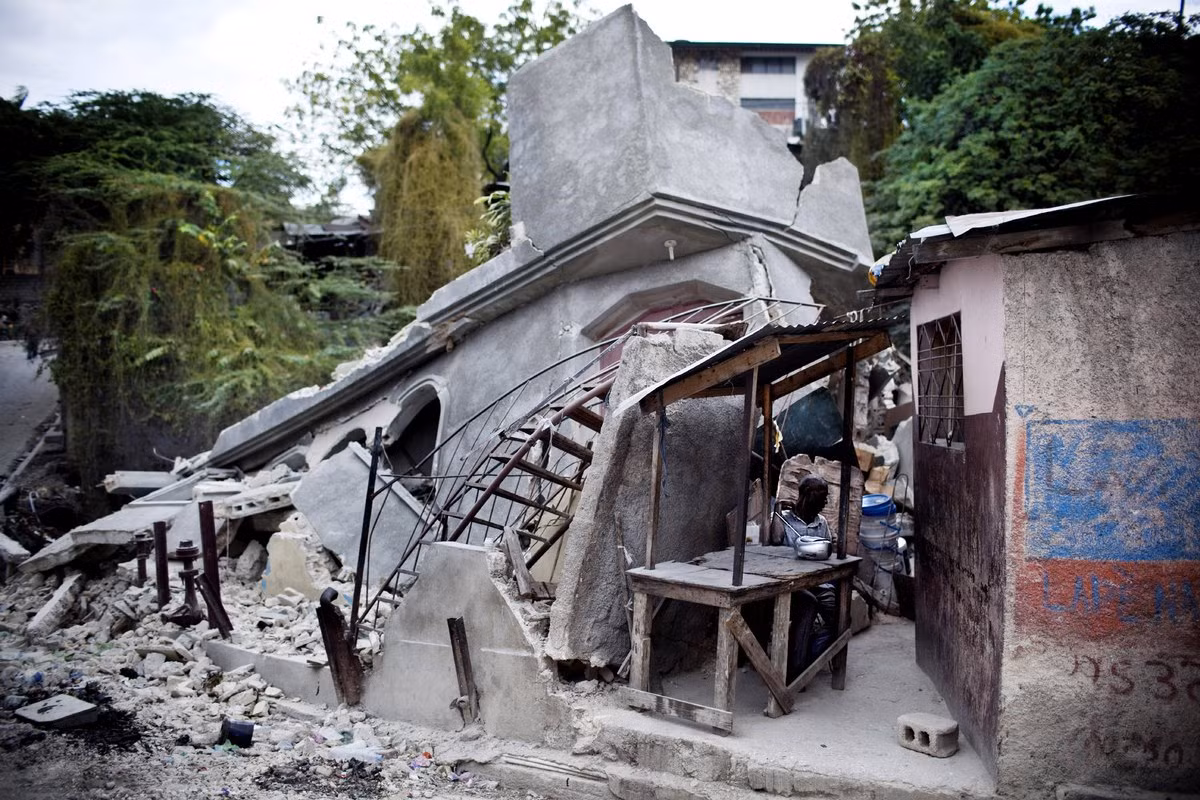 Một người đàn ông Haiti ngồi lặng trong cửa hàng dựng tạm, xung quanh là đống đổ nát sau trận động đất ở Port au Prince ngày 1/2/2010 – hơn nửa tháng sau khi trận động đất kinh hoàng diễn ra.