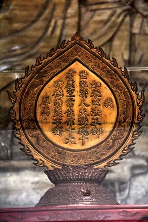 Chúng ta sẽ thấy sự pha trộn ấy thể hiện khá rõ ở những hiện vật quý giá ở các chùa xứ Quảng. Đây là dịp rất hiếm để được xem những sắc thái phong phú trong tạo hình tượng Phật của các nghệ nhân cách đây vài thế kỷ. Ảnh: Trái tim lửa bằng đồng rập ngự bút của Minh Mạng ghi nhận lòng thành kính của người nước Nam trước Đức Phật Tổ. Quả tim lửa này được để tại chùa Tam Thai xây dựng từ năm 1630, được vua Minh Mạng ban sắc tứ, cổ tự là quốc tự của triều đình và ban cho chiếc kim bài quý. 200 năm qua, quả tim lửa này là một báu vật trong đời sống tâm linh của người dân sống trong vùng Ngũ Hành Sơn. Các chuyên gia Bảo tàng Đà Nẵng đã có kế hoạch nghiên cứu và làm hồ sơ đề xuất công nhận chiếc kim bài này là bảo vật quốc gia.