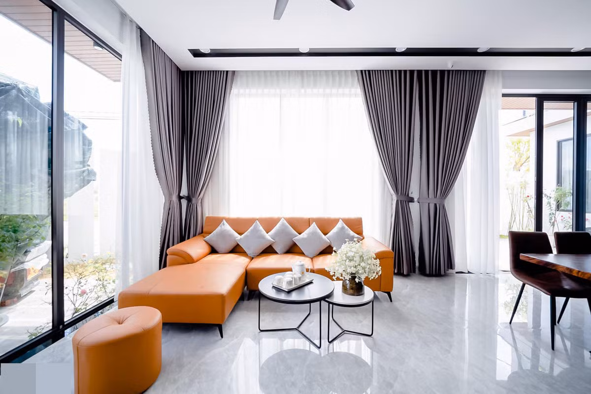 Màu cam của sofa phối với màu xám của rèm cửa, sàn nhà tạo nên sự tương phản rõ nét.
