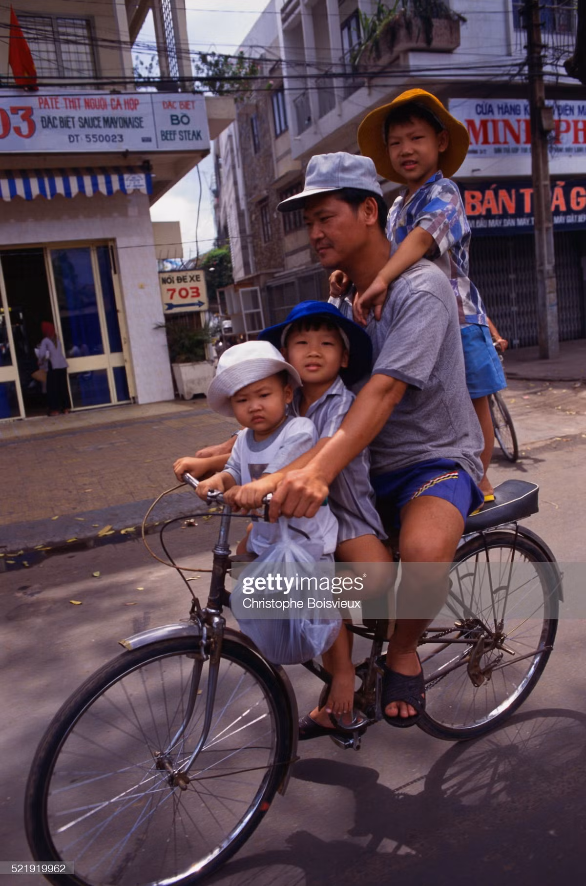 Người đàn ông và ba đứa trẻ trên chiếc xe đạp cũ.