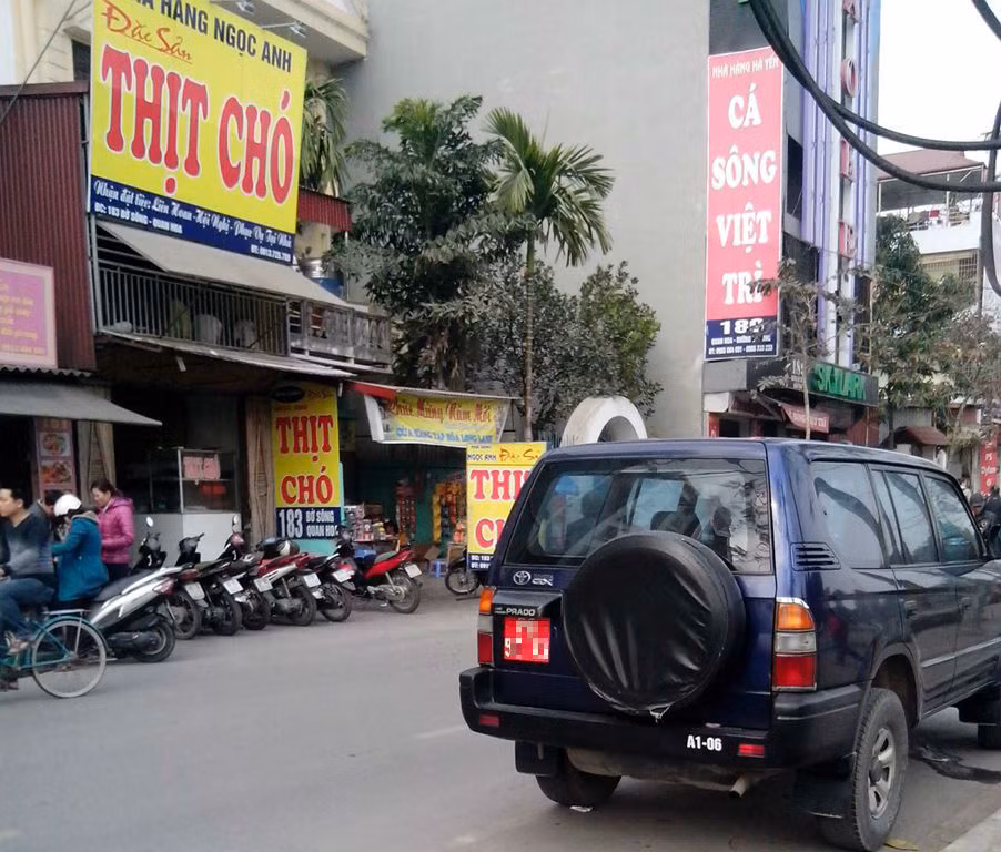 Một chiếc xe biển đỏ thuộc biên chế trong quân đội đang đợi "sếp" trước một quán thịt chó trên đường Bờ sông Quan Hoa (Cầu giấy).