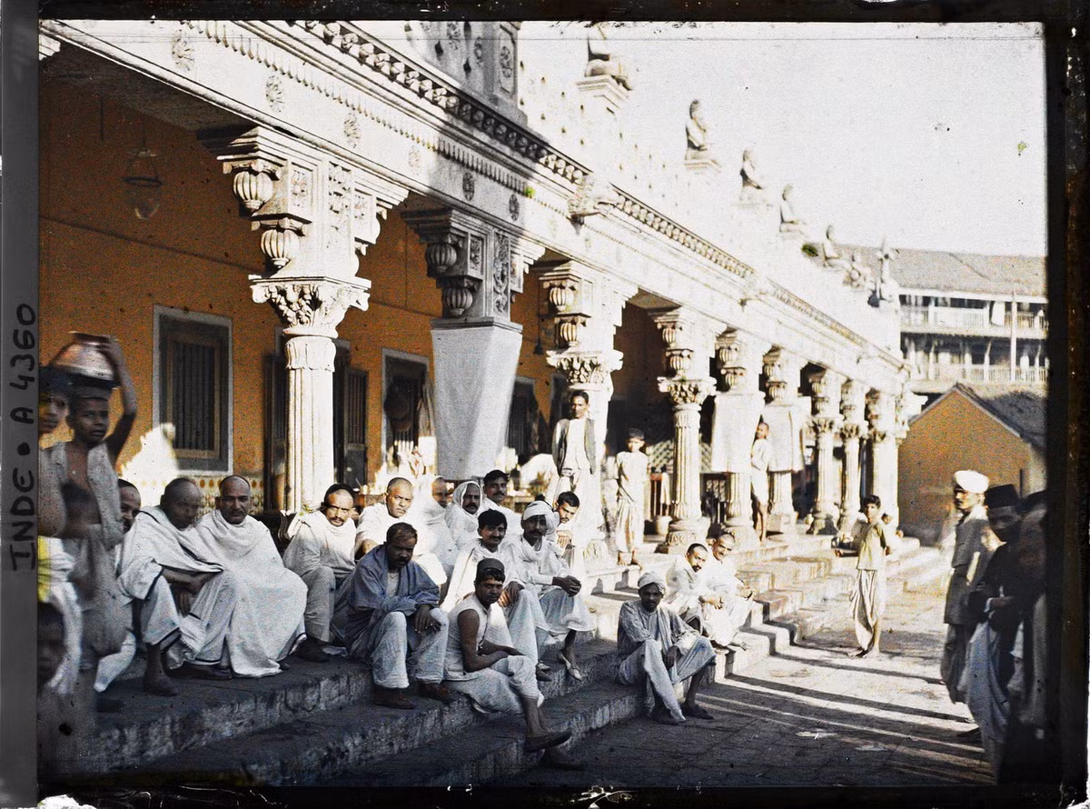 Những người đàn ông mặc đồ trắng ngồi trên bậc thềm của một ngôi đền Hindu.