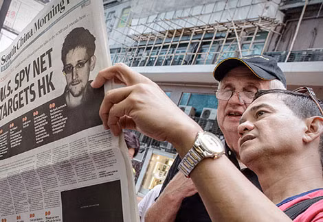 Hai người đàn ông chăm chú đọc tờ South China Morning Post có bài đăng về người thổi còi Snowden hồi tháng 6.