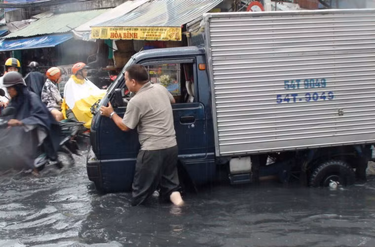 Tài xế xe tải phải hì hục thuê người đẩy xe ra khỏi vùng ngập trên đường Hòa Bình.