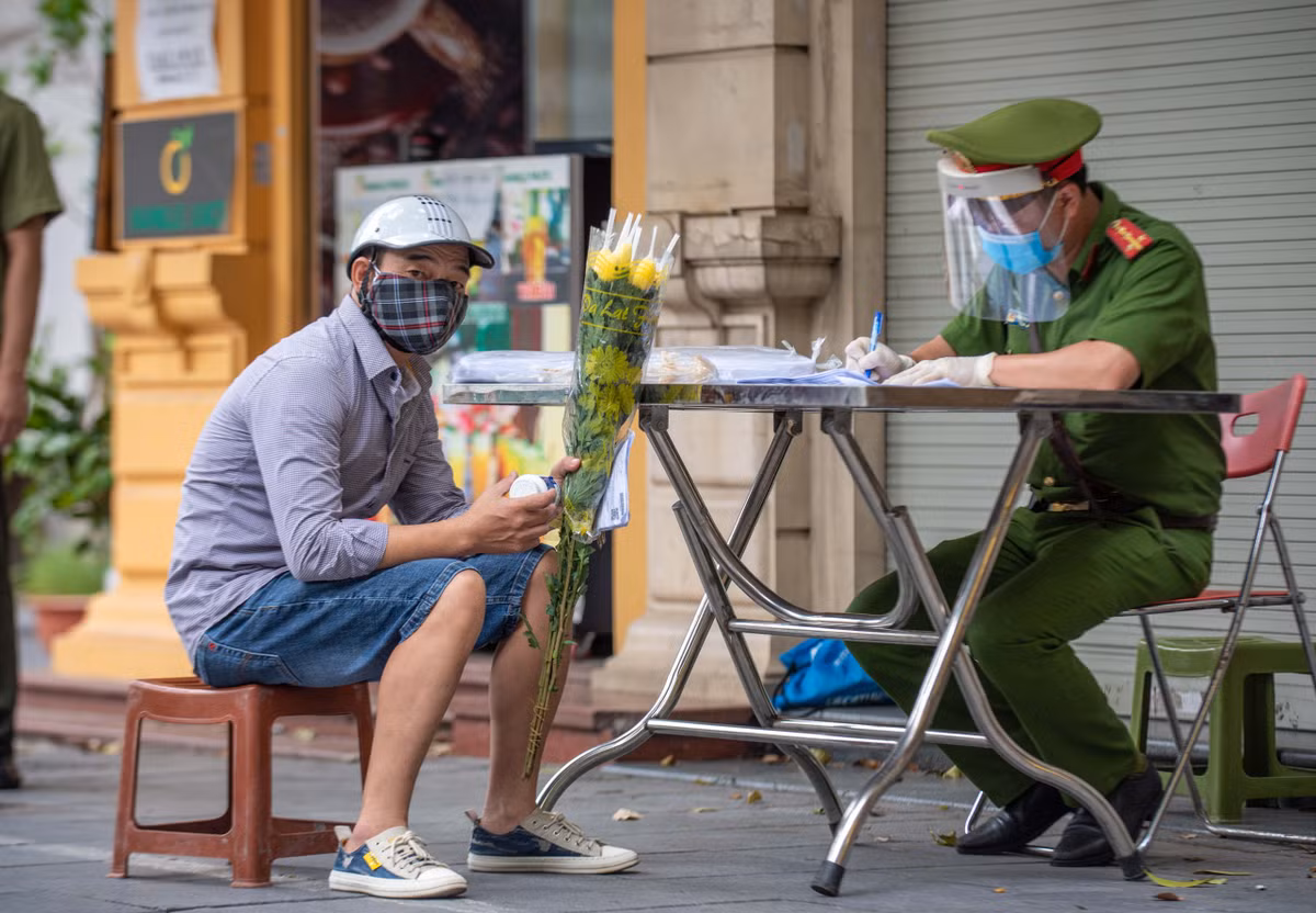 Khoảng 2 giờ ghi nhận tại chốt, tổ công tác vẫn phát hiện một số trường hợp vi phạm quy định phòng chống dịch Covid-19. Trong ảnh, ông Tạ Mạnh Hùng (đội mũ bảo hiểm) trình bày với cán bộ tại chốt đi mua thuốc. Tuy nhiên, người này ra đường không có giấy, lịch trình di chuyển từ nhà đến nơi mua thuốc không hợp lý nên tổ lập biên bản.
