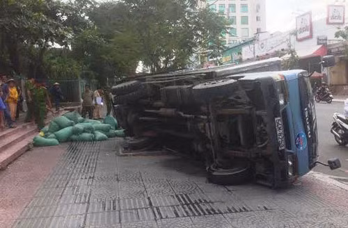 Trong lúc lui xe lên vỉa hè, chiếc xe tải chở nước đá sụp cống lật nhào.