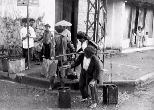 Những người phụ nữ gánh nước trên vỉa hè phố cổ, thập niên 1920-1930. Ảnh: Charles Peyrin