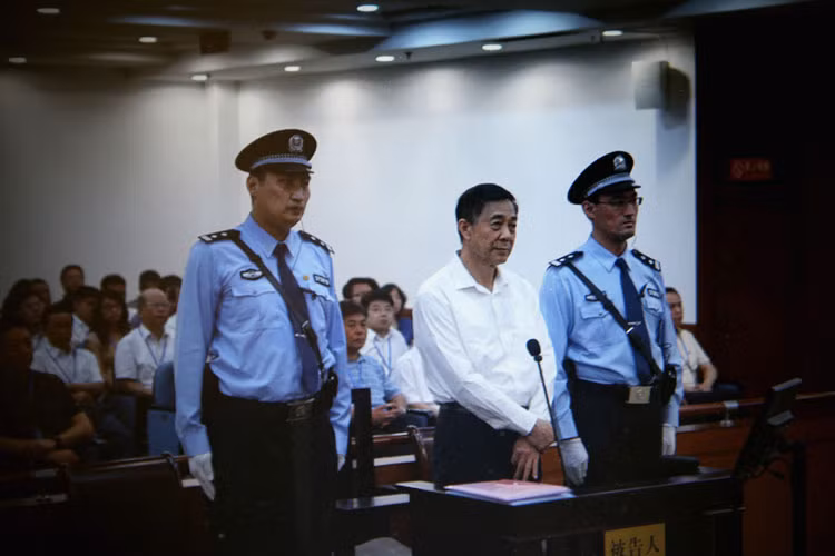 Ông Bạc Hy Lai lọt thỏm giữa 2 cảnh vệ cao lớn bất thường trong phiên xử đầu tiên vào ngày 22/8. Ngôi sao sáng một thời trên sân khấu chính trị Trung Quốc đang bị xét xử tội tham ô, biển thủ công quỹ, lạm quyền.
