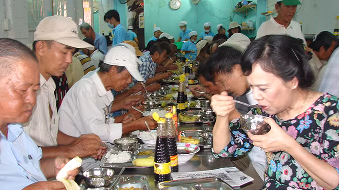 Bà Mai Thị Hạnh (bìa phải) dùng cơm với người nghèo trưa 4/7. Ảnh: M.Hương.