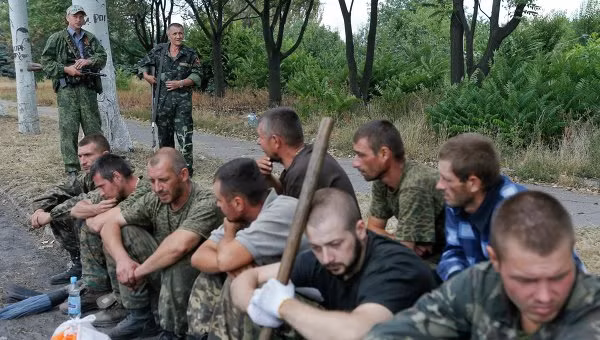 Các binh sĩ Ukraine ngồi bệt dưới đất khi họ bị dân quân bắt đi quét dọn đường phố ở Snizhne, tỉnh Donetsk.