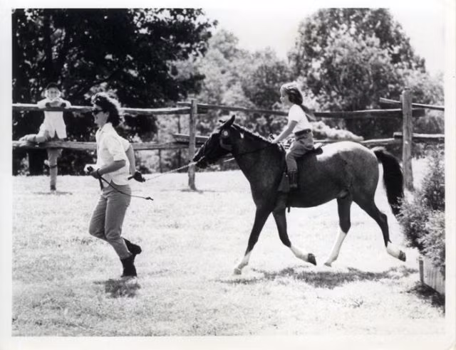 Đệ nhất phu nhân Jackie Kennedy dắt chú ngựa Macaroni cùng Caroline Kennedy cưỡi phía trên ở Wexford, Virginia.