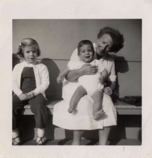 Bà bảo mẫu Maud Shaw nựng John F. Kennedy Jr. trong khi Caroline Kennedy ngồi bên cạnh.