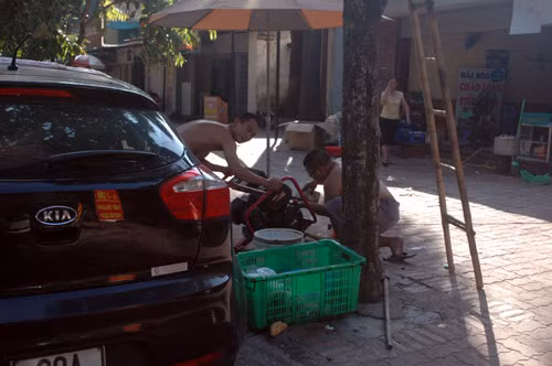 2 người đàn ông khẩn trương đổ nhớt cho máy phát điện trên đường Tô Hiệu, Nghĩa Tân, quận Cầu Giấy.