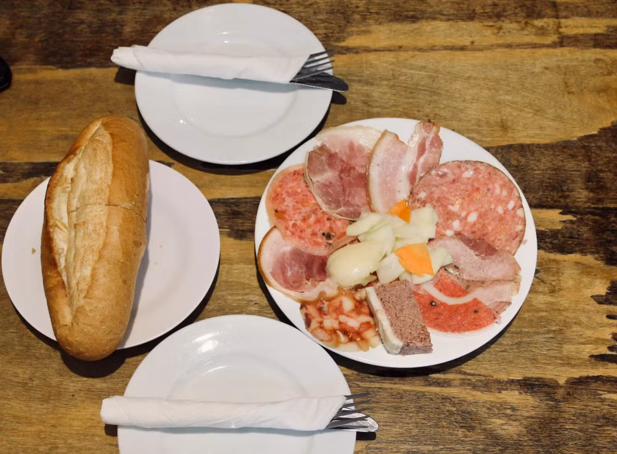 Một phần bánh mì ở đây gồm nhiều loại đồ ăn đi kèm như pate gan ngỗng, thịt xông khói, xúc xích, jambon,… ăn kèm một chút đồ chua gồm đu đủ, cà rốt muối và sốt mayonaise tươi đặc trưng của nhà hàng.