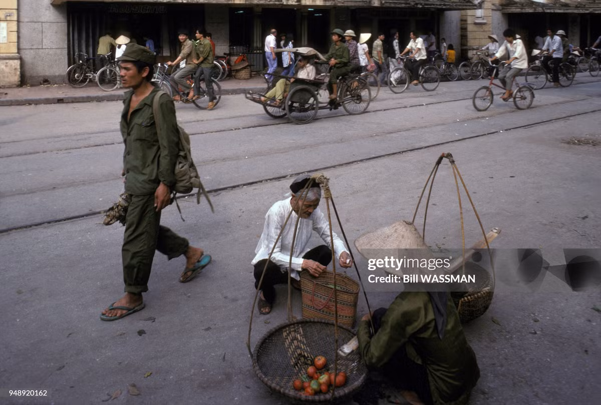 Cụ bà mua rau quả bên lề đường.