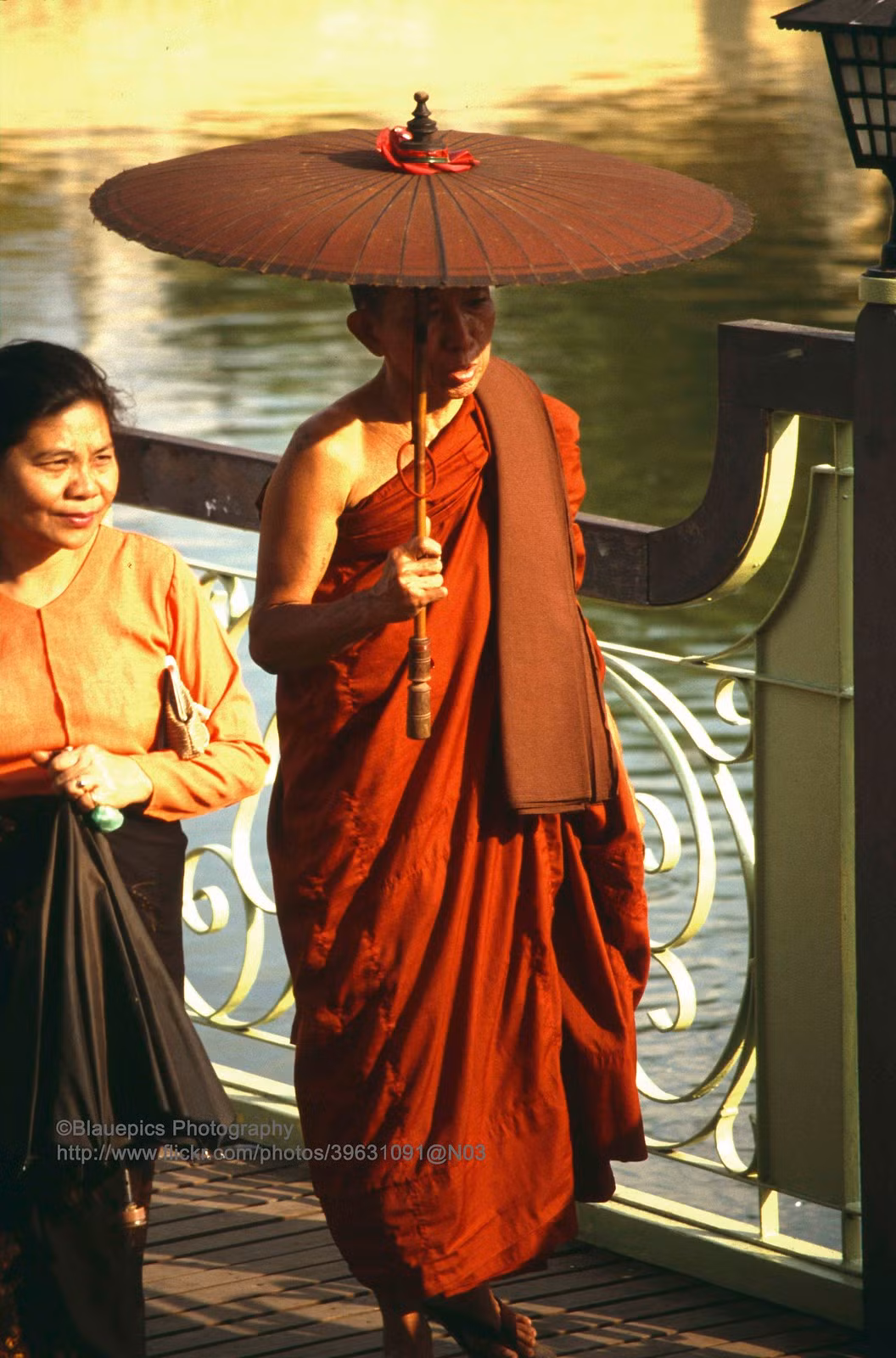 Nhà sư cầm ô đi bên hồ.
