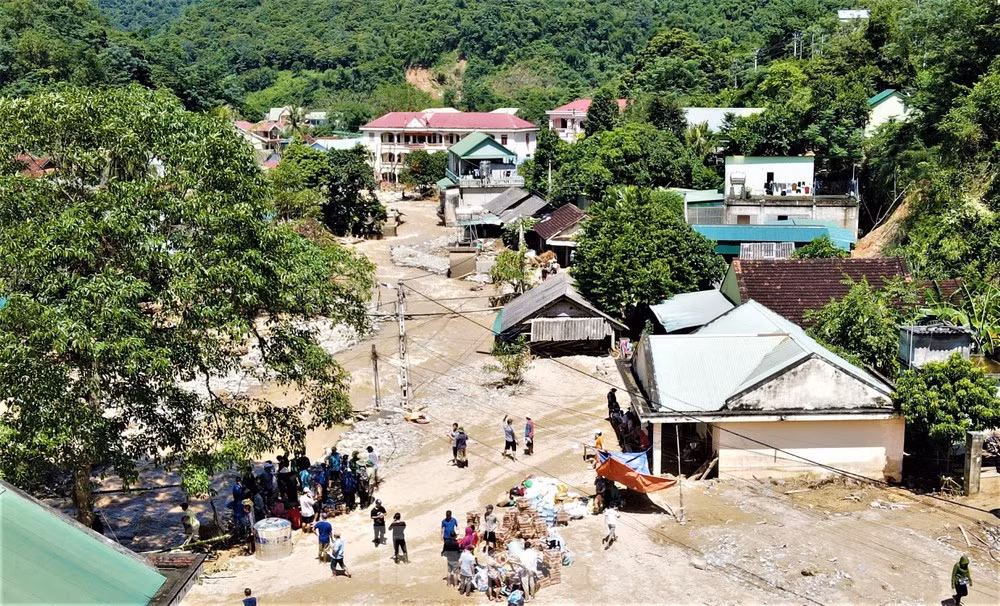 Với học sinh mầm non, do đặc thù độ tuổi của các em còn quá nhỏ, điểm trường chưa khắc phục được hư hỏng nên phòng dự kiến trước mắt sẽ mượn nhà dân học nhà sàn để dạy học cho học sinh. Trong ảnh là điểm trường mầm non ở xã Tà Cạ (góc phải) ngập trong lớp bùn dày.