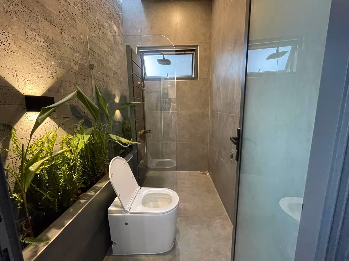 Phòng vệ sinh chung có vách tắm kính và bồn cây dưới giếng trời nhỏ. Giếng trời có tác dụng lọc không khí, đối lưu gió và hút mùi hôi hiệu quả.