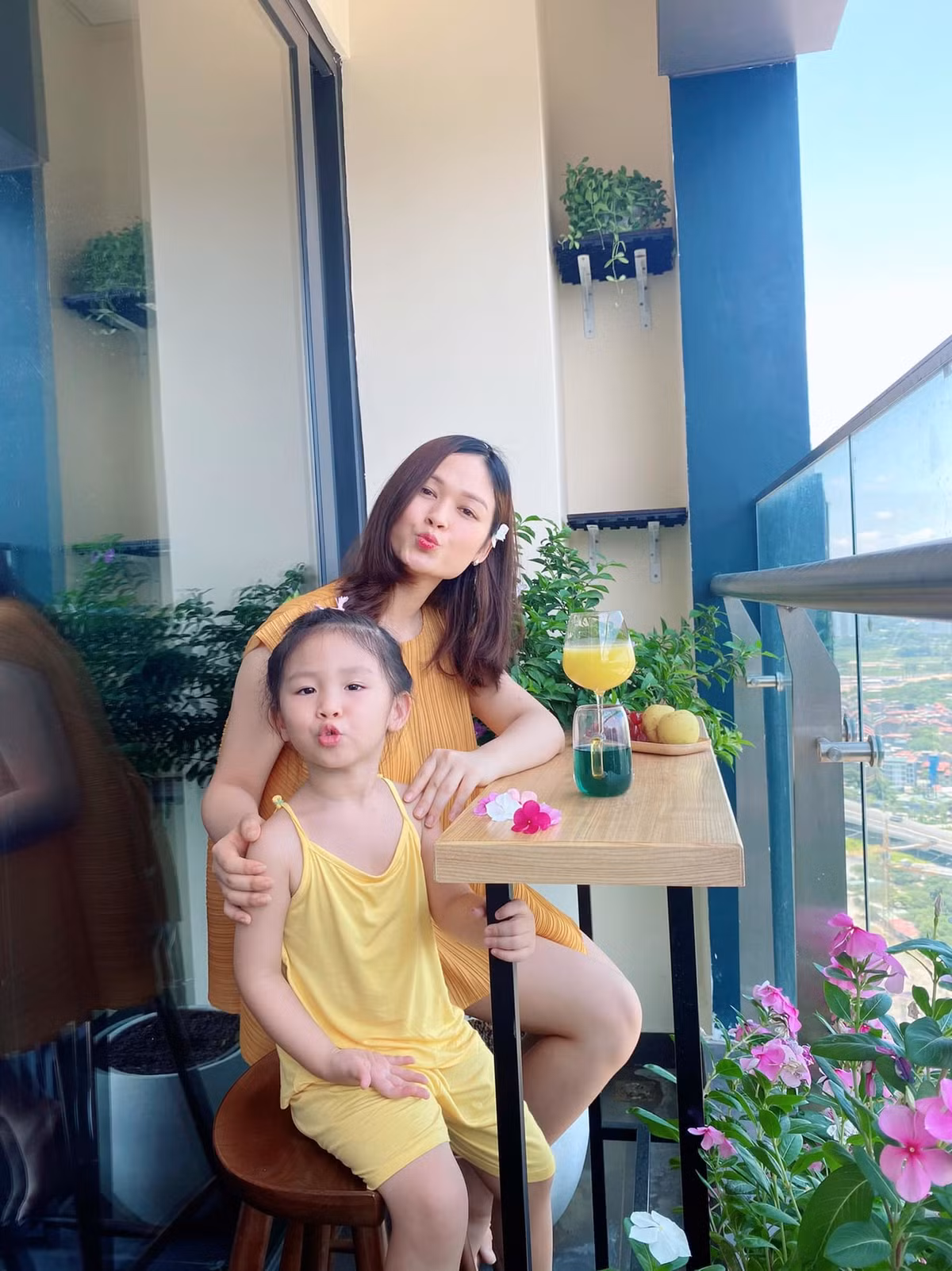 Ban công thiết kế đơn giản với bàn gỗ dài, vài chậu hoa, cây cảnh nhưng vẫn đủ tạo thành góc thư giãn, chụp ảnh đẹp long lanh.