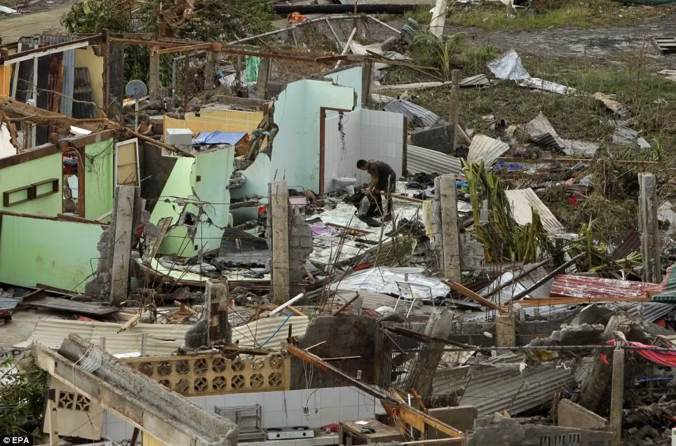 Một người đàn ông ở thành phố Tacloban bới tìm đồ trong đống đổ nát, tan hoang sau siêu bão Haiyan.