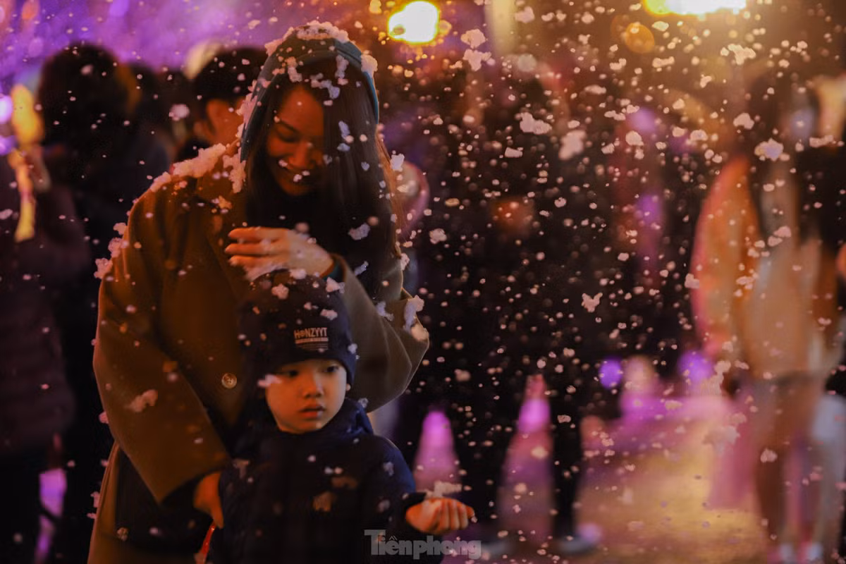Người dân thích thú chụp ảnh cùng với những bông tuyết trắng...