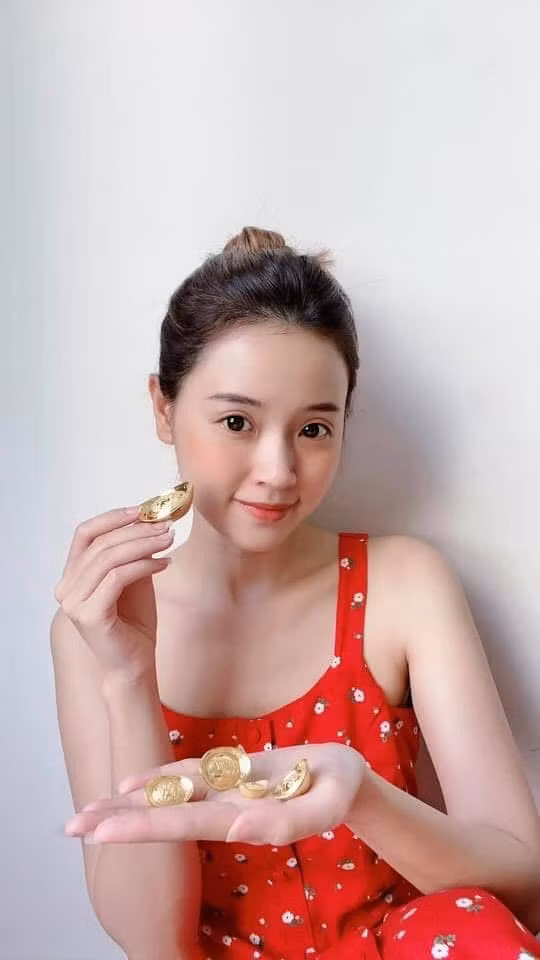 Midu diện trang phục đỏ tay cầm những thỏi vàng: "Ngày vía Thần Tài lấy mấy thỏi vàng xinh xinh ra đếm lấy hên".