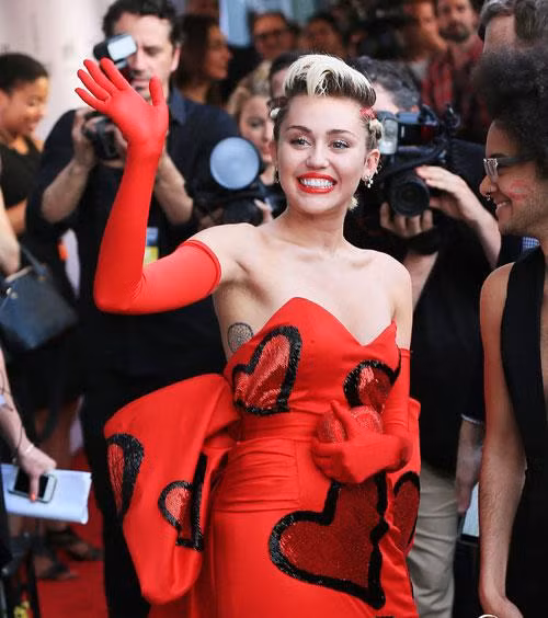 Trong một sự kiện từ thiện, Miley Cyrus xuất hiện trong bộ đầm dài cúp ngực đi cùng găng tay dài vô cùng quyến rũ nhưng lại lộ rõ bộ vi-ô-lông nách dài ngoằng, rậm rạp dưới cánh tay.