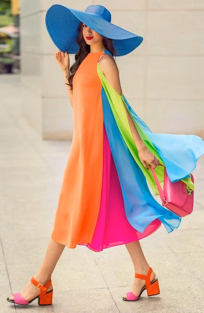 Chiếc đầm trông như 7 sắc cầu vồng bay bổng được nàng á hậu mix cùng túi xách, sandal, nón vành rộng đúng chất quý cô thời thượng.