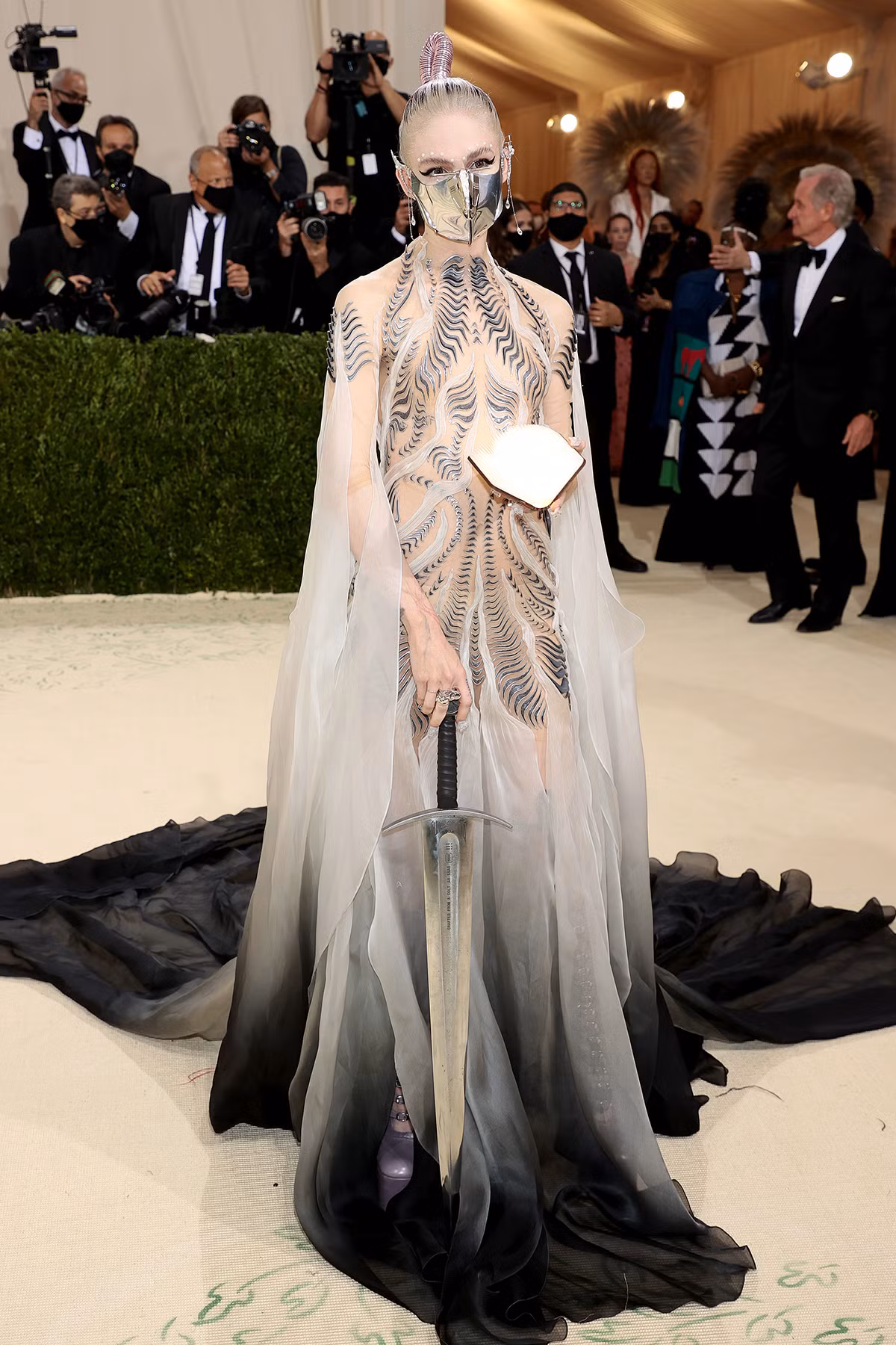 Ca sĩ Grimes, bạn gái tỷ phú Elon Musk đeo khẩu trang cách điệu mang theo cả gươm đến sự kiện.