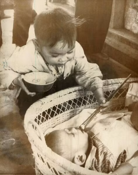 Bé Nam dùng đũa bón thức ăn cho em gái mình tại một trung tâm cứu trợ quốc tế dành cho trẻ em ở Quy Nhơn.