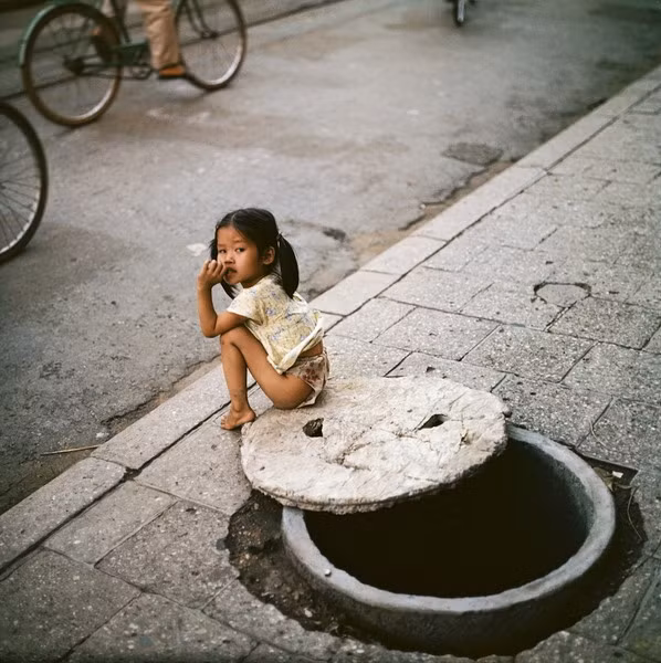 Bé gái ngồi bên miệng hầm trú ẩn.
