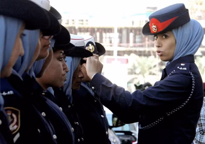 Một nữ cảnh sát giúp đồng nghiệp chỉnh mũ bên ngoài trụ sở tòa án ở thủ đô Manama, Bahrain.