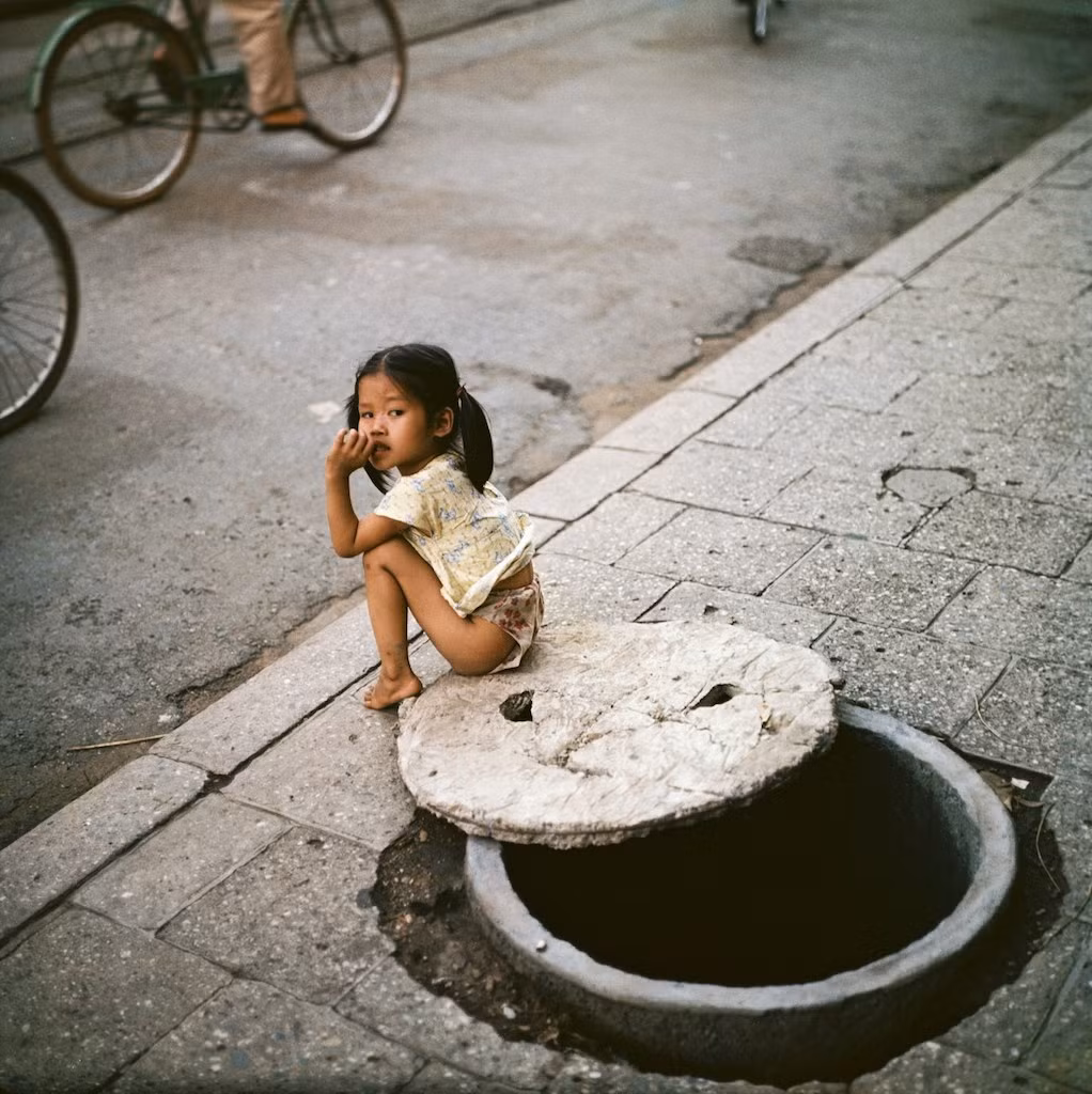 Bé gái ngồi bên miệng hầm trú ẩn.