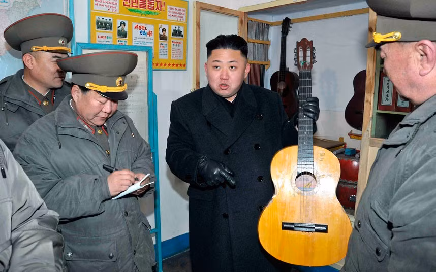 Nhà lãnh đạo vui vẻ xem xét một cây guitar trong chuyến thăm một đơn vị quân đội trên đảo tiền tiêu Wolnae.