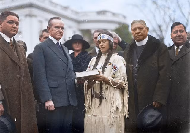 Người phụ nữ Mỹ bản địa đứng bên Tổng thống Hoa Kỳ Calvin Coolidge trong bức ảnh chụp năm 1923, trước khi Đạo luật công dân Anh-điêng được ký. Ảnh: Royston Leonard.