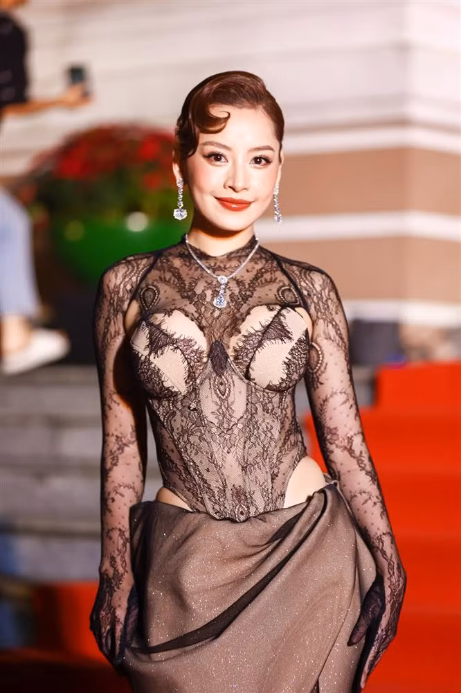 Trang phục như bodysuit ren tưởng không hở mà hở không tưởng vì xuyên thấu gần như toàn bộ thân trên kết hợp cùng chân váy quấn bên dưới.